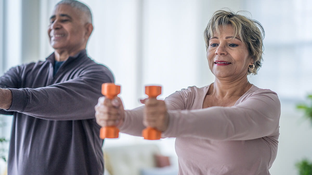 Older adults exercising with dumbbells during a fitness class.